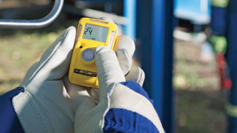 Mid-shot of a Honeywell BW Clip gas detector grasped in a worker’s hand.