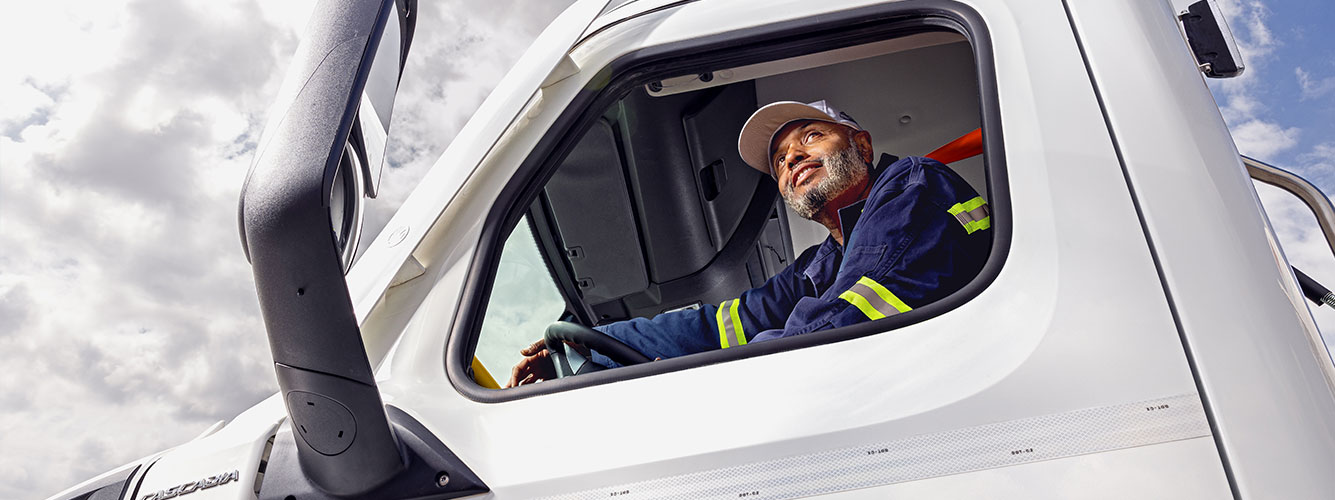 Airgas CDL truck driver sits in his truck cab smiling and looking up at the sky. 