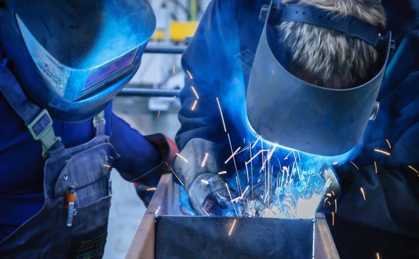 A welding instructor and student practicing welding techniques