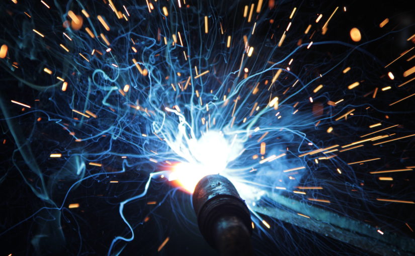 A close up of a MIG welding gun creating sparks