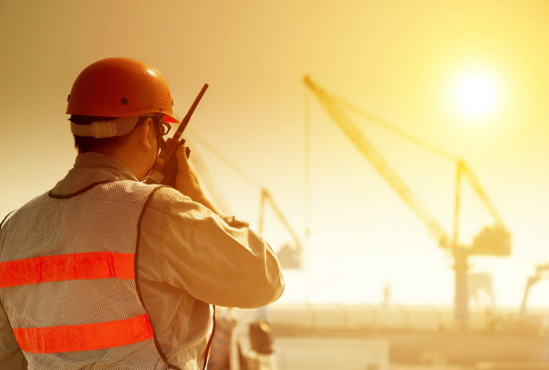 A construction worker uses his radio while working in high heat outdoor conditions.